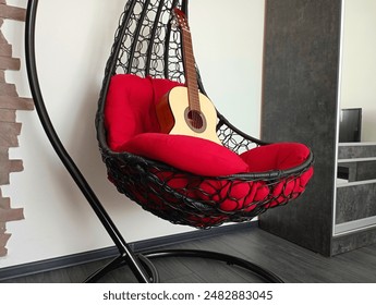 Interior in the room. In the black chair of the cocoon on the red pillow is a musical instrument, the guitar. - Powered by Shutterstock
