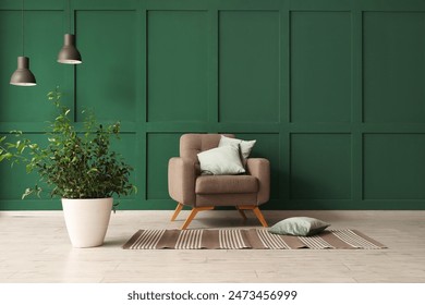 Interior of room with cozy armchair with pillows and houseplant near green wall