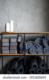 the interior of the room is a studio for sports yoga or stretching. table rack with decor candles and accessories for classes - gray support cubes, rubber mats and plaids