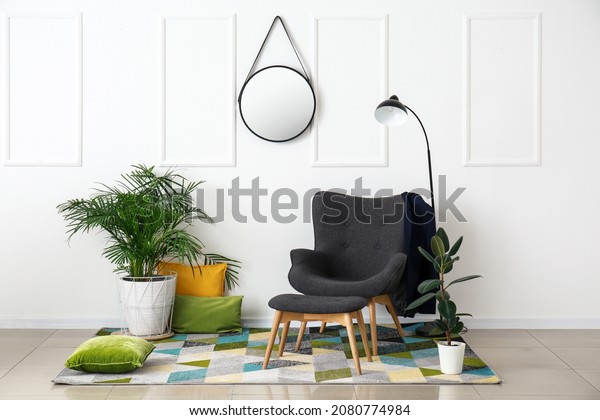 Interior of room with stylish armchair and\
houseplants near white\
wall