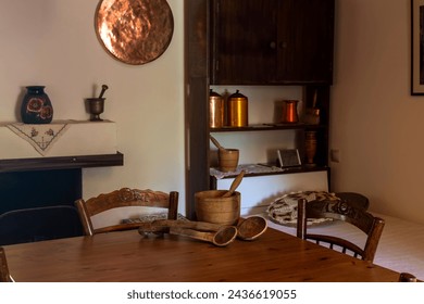 The interior of a rural, old house with a table, chairs, a fireplace, a wardrobe and a bed close-up