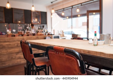 Interior Of A Rustic Coffee Shop With A Large Wooden Table In Foreground