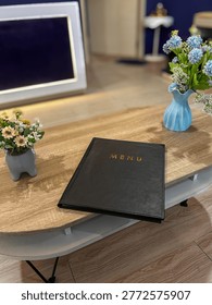 Interior scene featuring a menu folder on a wooden surface with decorative plants.