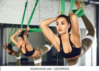 The interior shooting of an two women practices different inversion antigravity yoga with a hammock in yoga studio. The balance between mental and physical, one person effort and achievement concept
