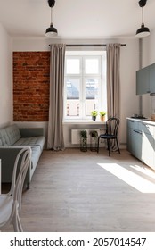 Interior Of Small Apartment In Loft With Brick Wall And Window. Kitchen And Cozy Living Room With Wooden Floor. Vertical.