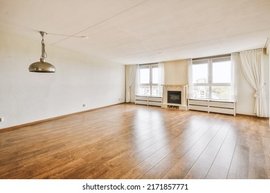 Interior of spacious light room with electric fireplace, windows with curtains and parquet floor