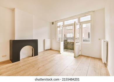 Interior Of Spacious Light Room With Fireplace And Elegant Chandelier Against Balcony Door And Windows