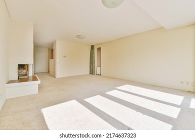 Interior Of Spacious Light Room With Fireplace And Elegant Chandelier Against Balcony Door And Windows