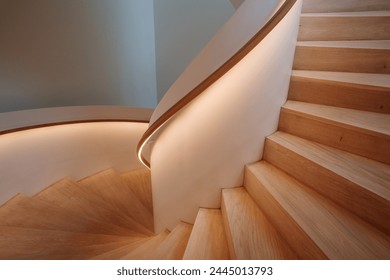 Interior staircase featuring a smooth curve, with warm light emanating from the built-in illumination along the handrail.  - Powered by Shutterstock