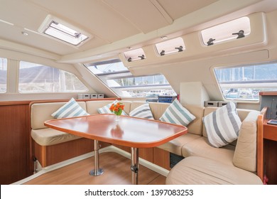 Interior of a stunning modern private sailing catamaran, portraying the saloon with big lounging area with cushions 