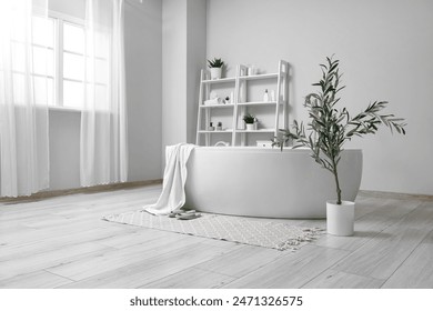 Interior of stylish bathroom with bathtub, shelving unit and olive tree - Powered by Shutterstock