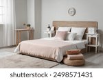 Interior of stylish bedroom with bed, pillows, bedside tables and clock on white wall