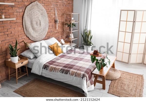 Interior of stylish bedroom with folding\
screen and houseplants