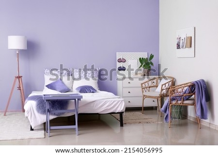 Interior of stylish bedroom with lilac wall