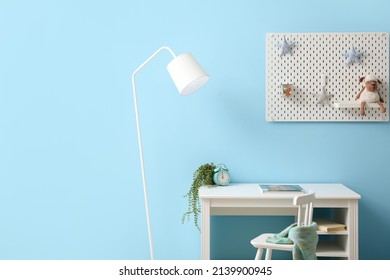 Interior Of Stylish Children's Room With Desk And Hanging Pegboard On Blue Wall