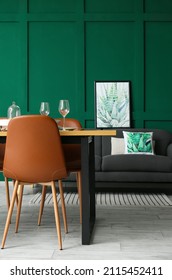Interior of stylish dining room with table, sofa and green wall