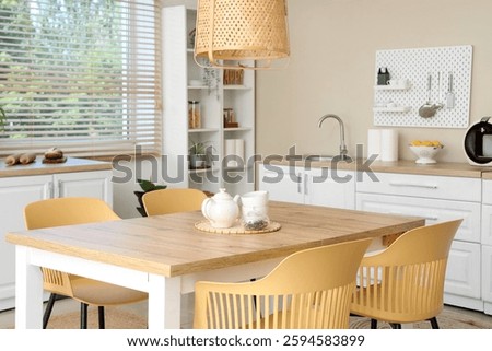 Interior of stylish kitchen with dining table, white counters and peg board