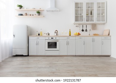Interior of stylish kitchen with light walls, white furniture with utensils and fruits, shelves with crockery and plants in pots, refrigerator in dining room scandinavian design, empty space - Shutterstock ID 1922131787