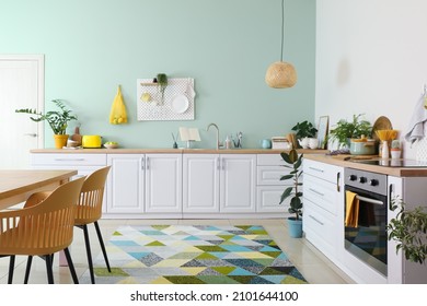 Interior Of Stylish Kitchen With White Counters And Hanging Peg Board On Green Wall