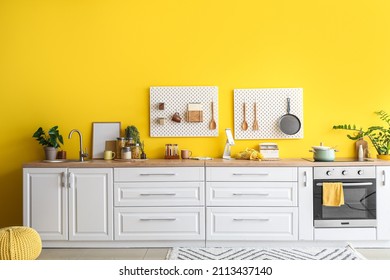 Interior Of Stylish Kitchen With White Counters, Peg Boards And Yellow Wall