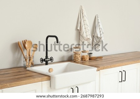 Interior of stylish kitchen with white counters, utensils and sink