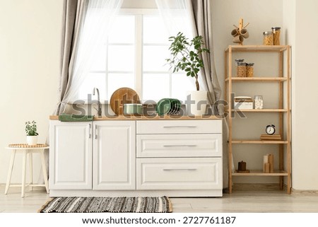 Interior of stylish kitchen with white counters, window, sink and shelving unit