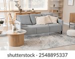 Interior of stylish living room with grey sofa and coffee table near window