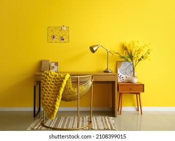 Interior of stylish office with modern workplace, golden lamp and yellow wall