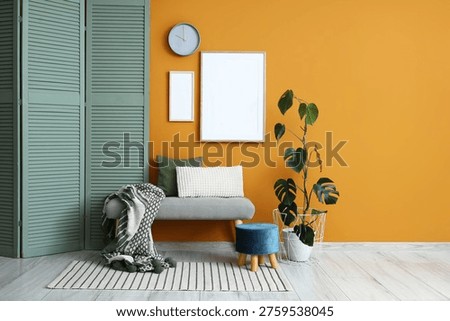 Interior of stylish room with clock, blank frames and soft bench