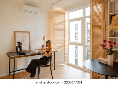 Interior Of Sunny Studio Apartment In Beige Tones With Working Place And Woman Spending Leisure Time At Home