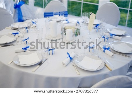 Interior, table and setup with plates at wedding reception for dining with cutlery arrangement. Layout, candlelight or centerpiece with napkin decoration, catering aesthetic and glassware at ceremony