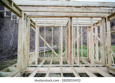 Interior timber frame house under construction, wooden studs and floor grid exposed, unfinished space representing housing development, architecture planning, investment and future living