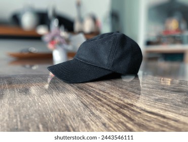 Interior top view visual image photo of a black cap hat down on a wood table in a house in close up with nobody around but during the bright day light