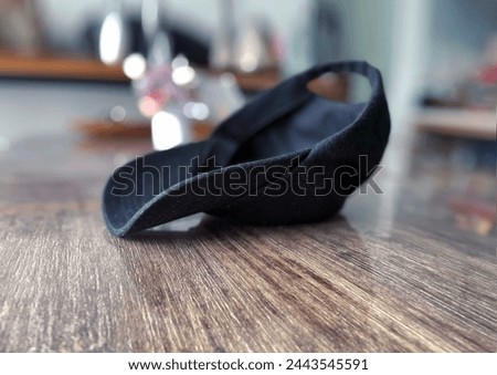 Interior top view visual image photo of a black cap hat upside down on a wood table in a house in close up with nobody around but during the bright day light