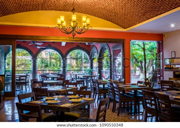 Interior of a traditional Mexican\
restaurant with tables and chairs, brick ceiling and\
chandellier
