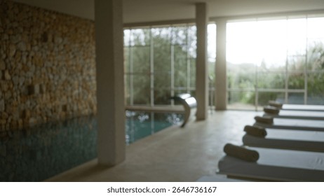 Interior of a tranquil spa with blurred background, featuring elegant chaise lounges and a serene pool area, bokeh effect softening the natural lighting and luxurious ambiance.