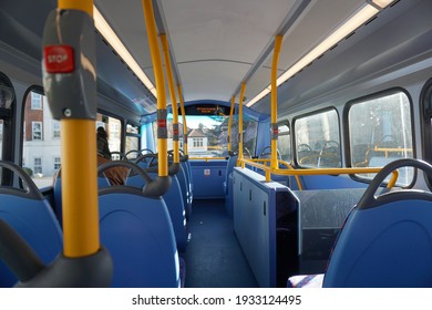 Interior of the upper deck of Double decker-bus. Taken from behind blue seats, yellow poles, red stop button public transportation 