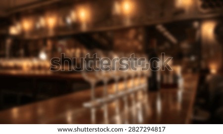 Interior view of a bar with warm lighting, showcasing rows of liquor bottles and glassware on shelves behind the counter.