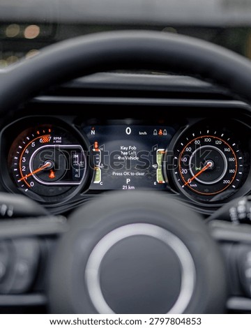 Interior view of car dashboard with analog speedometer and tachometer plus digital information display behind steering wheel