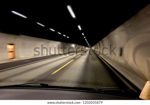 The\
interior view of a car inside a tunnel in Norway driving quickly\
with motion blur effect and slight window\
reflections