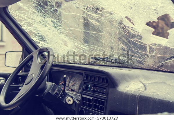 Interior view of a car with windshield\
smashed by a thief. Damaged glass from car\
theft