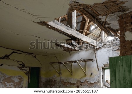 Interior view of a collapsed ceiling exposing wooden roof beams and rafters in an abandoned ruined building.