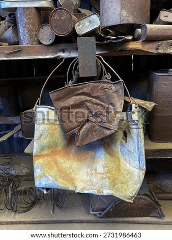 Interior view of a collection of old rusted tins, buckets and assorted containers on wooden shelves inside a shed