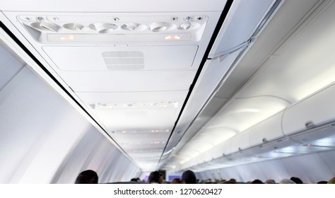 Interior view of a commercial airplane ceiling and seat headrests.