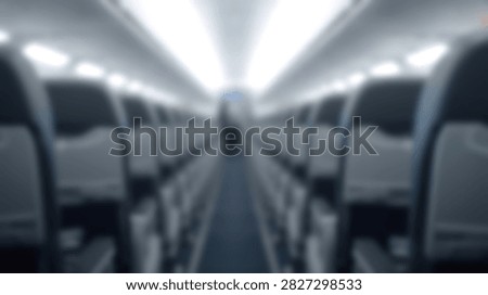 Interior view of an empty airplane cabin showing rows of seats on either side of the aisle, with overhead lights illuminating the space.