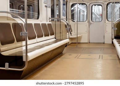 Interior view of an empty classic underground metro train carriage with rows of vacant brown seats, metal handrails, and clean floor