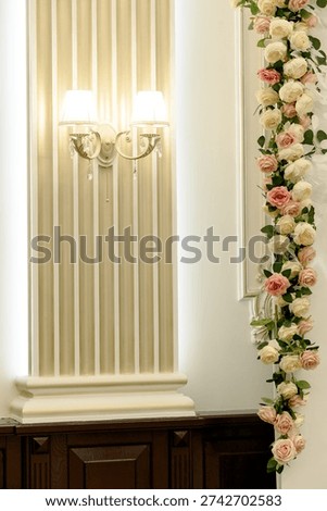 Interior view featuring a decorative wall with vertical paneling, wall sconces, and a floral arrangement of roses and greenery
