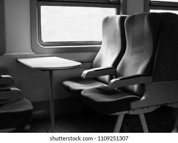 An interior view of a modern high speed train. Grey chairs.