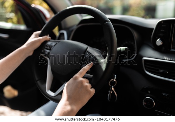 Interior view of a modern new car. Hands of a\
young woman on the car\'s\
wheel.