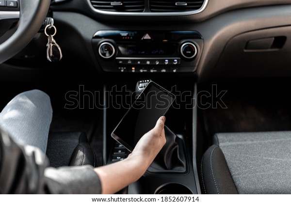 Interior view of a modern new car. A\
young woman using smartphone while driving the\
car